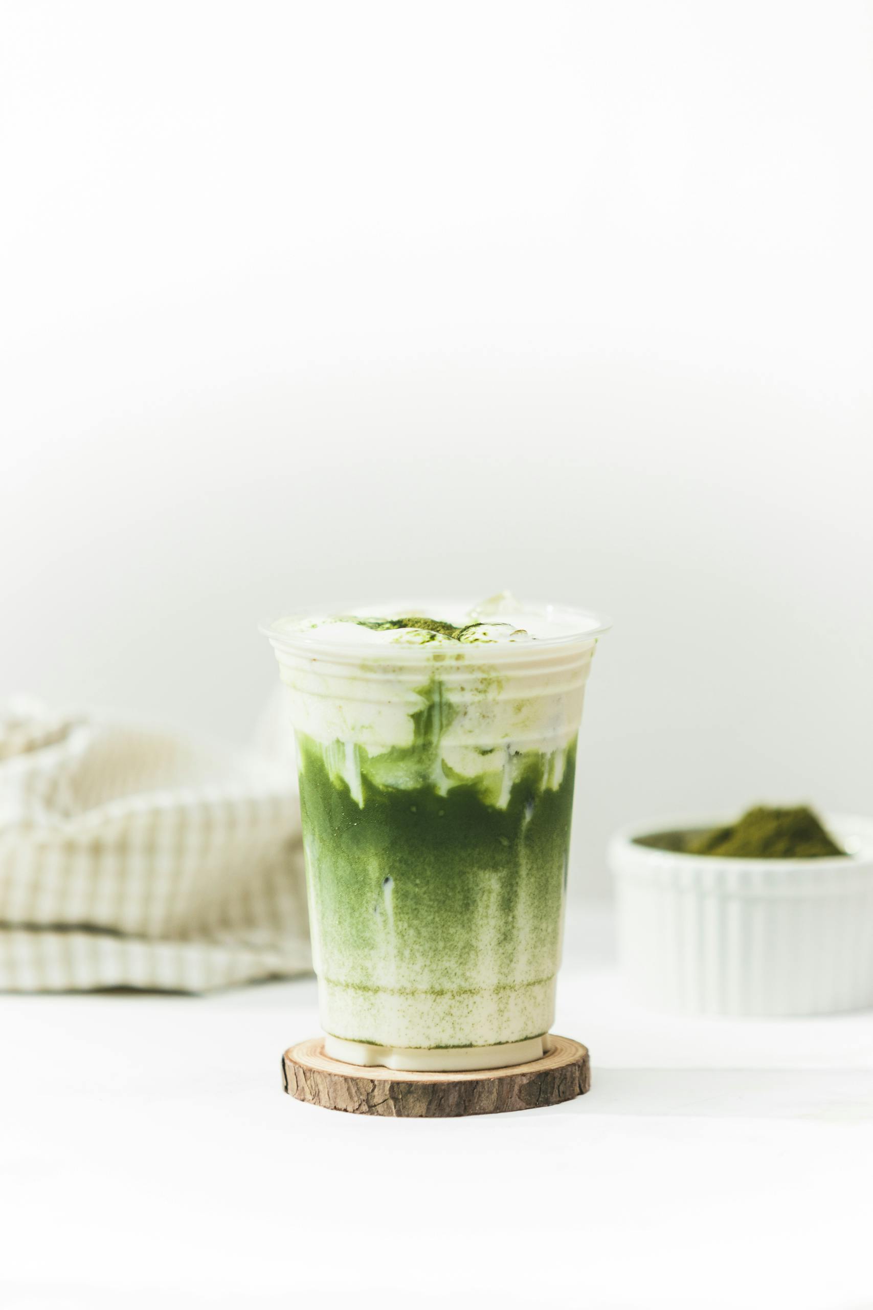 Close-up of a layered matcha latte in a clear cup, perfect for promoting health and wellness.