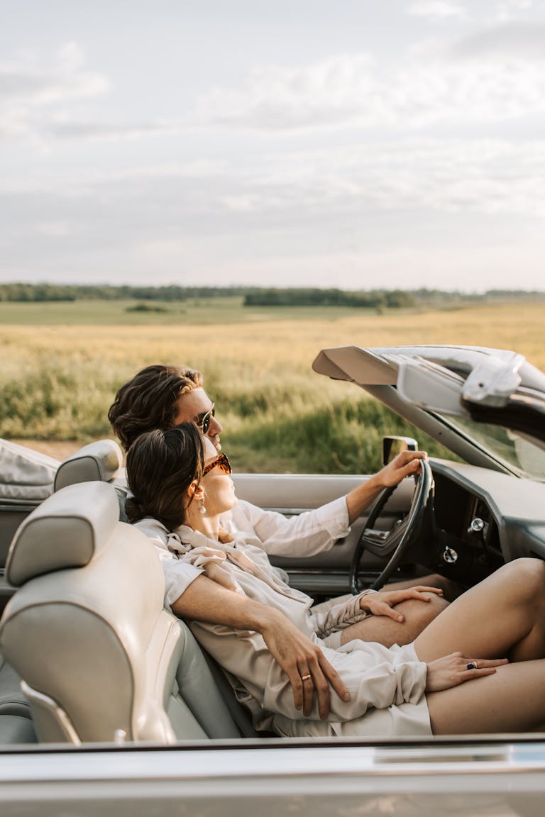 A couple enjoys a romantic drive through scenic fields in a stylish convertible.