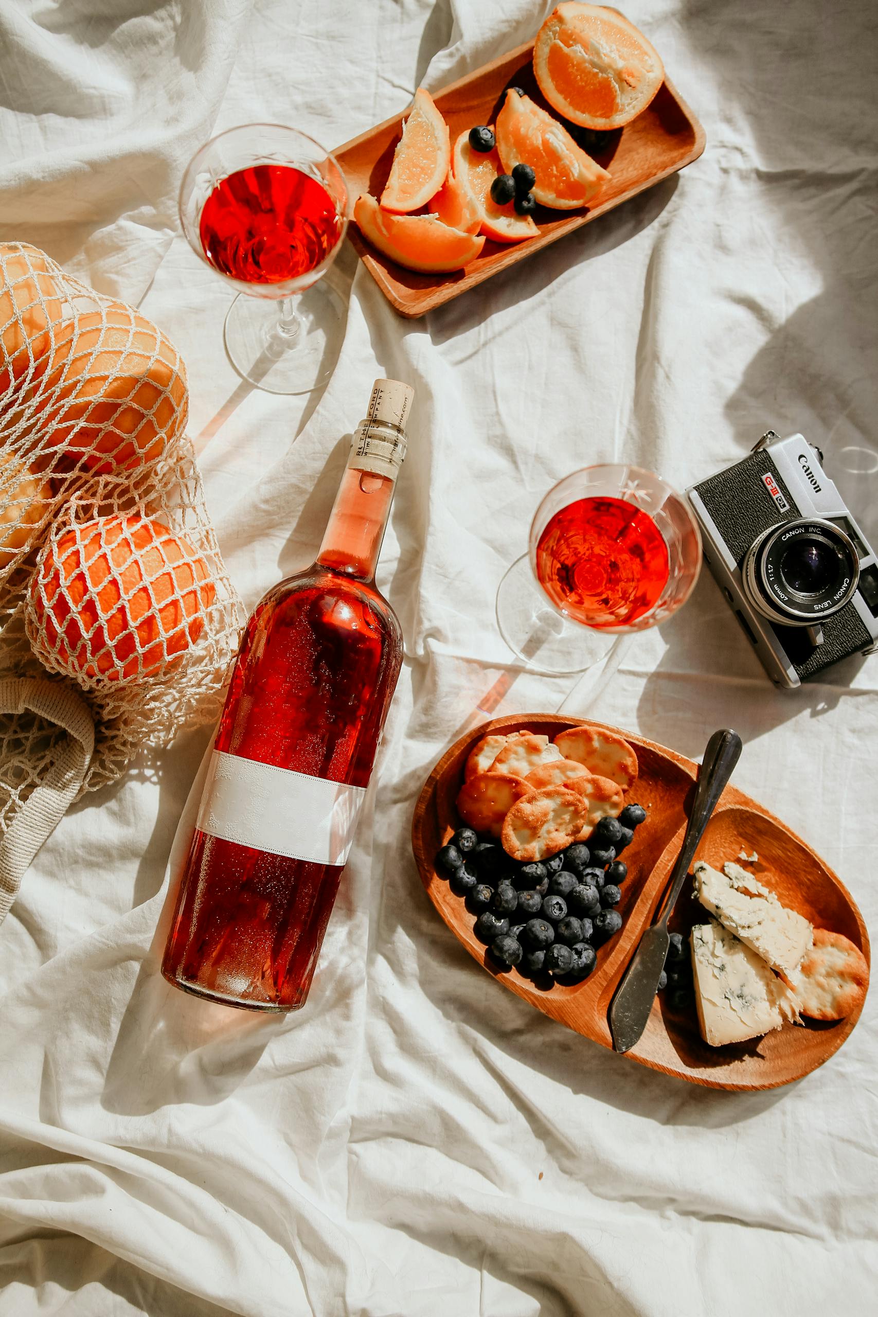 Stylish outdoor picnic in Napa featuring rosé wine, fresh fruits, and cheese for a summer delight.